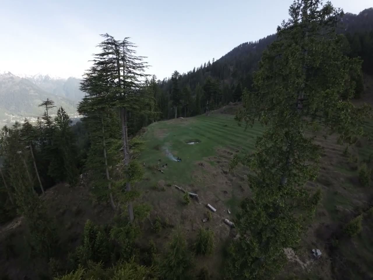 A forest clearing above the valley, smoke rising from a small fire.