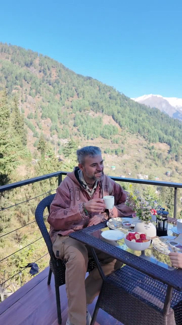 Two guests sharing breakfast on the deck, the valley behind them.