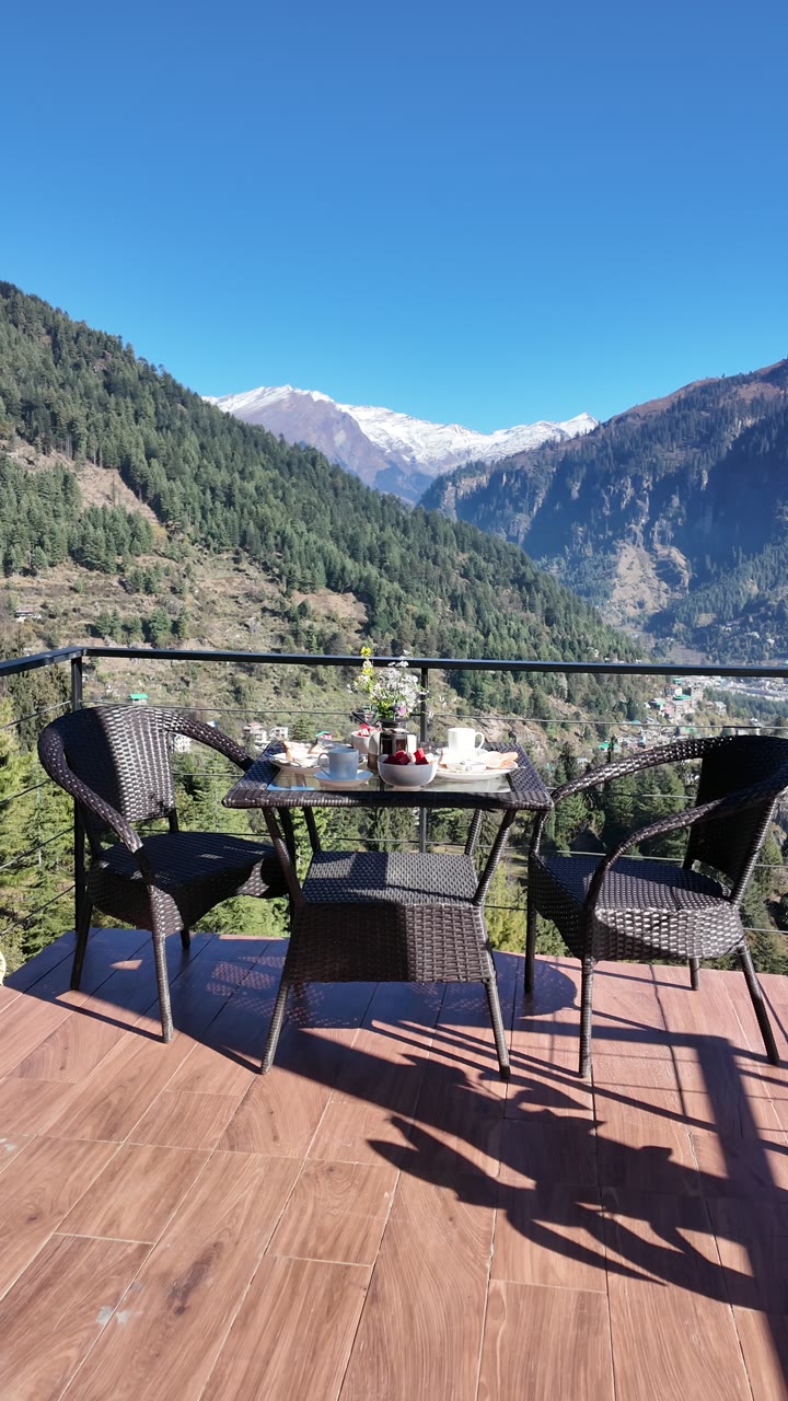 The deck table and chairs in morning shadow, snow peaks beyond.