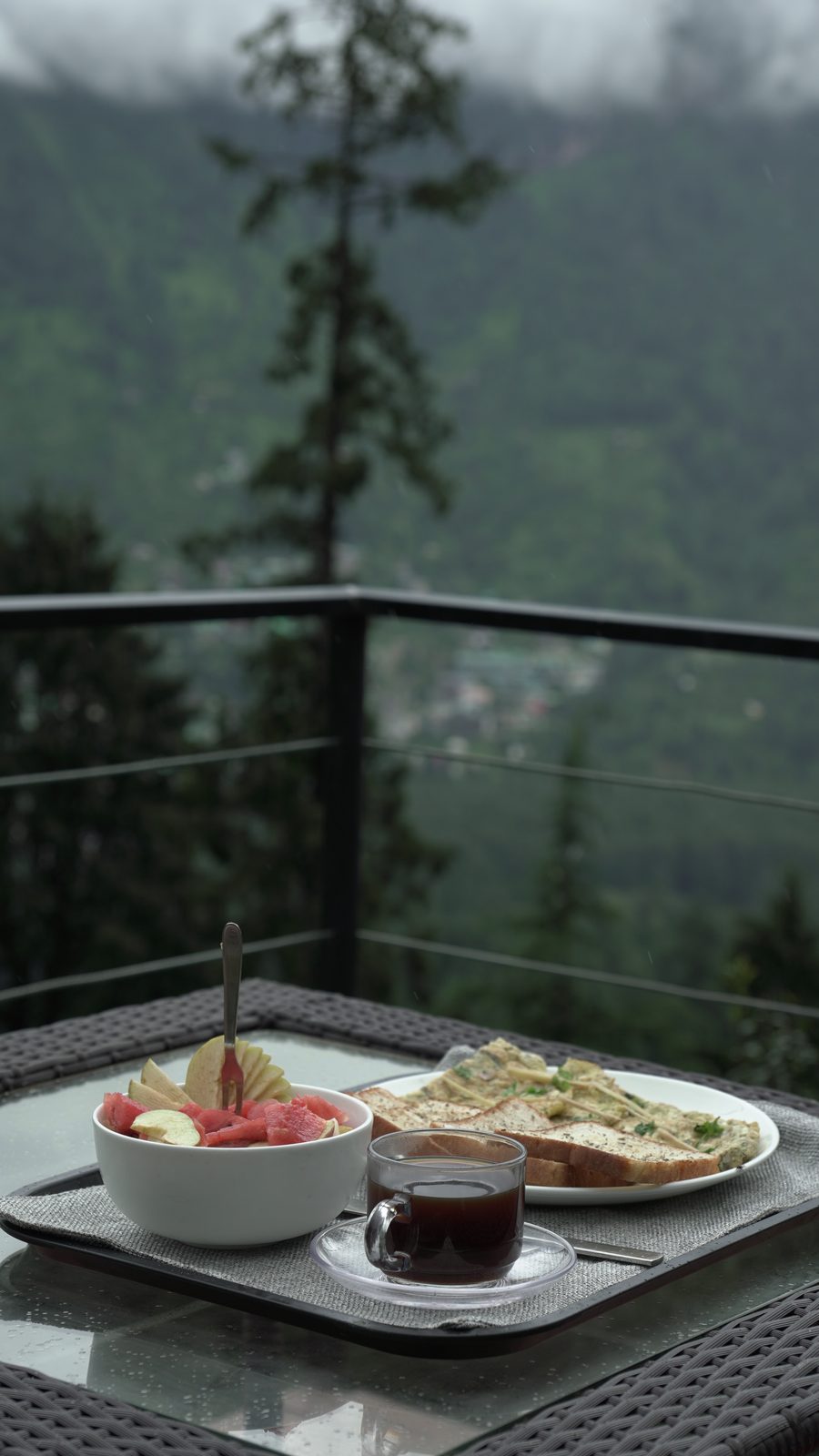 A breakfast tray of fruit, toast and tea on the deck in the mist.