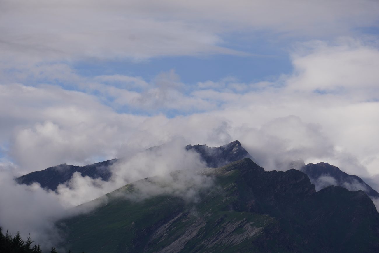 Cloud lifting off a green mountain peak.