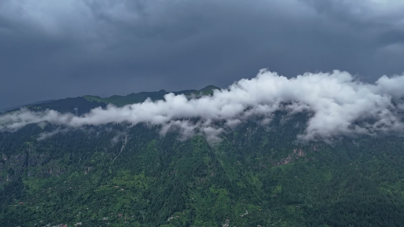 Heavy cloud rolling across a green mountain slope.
