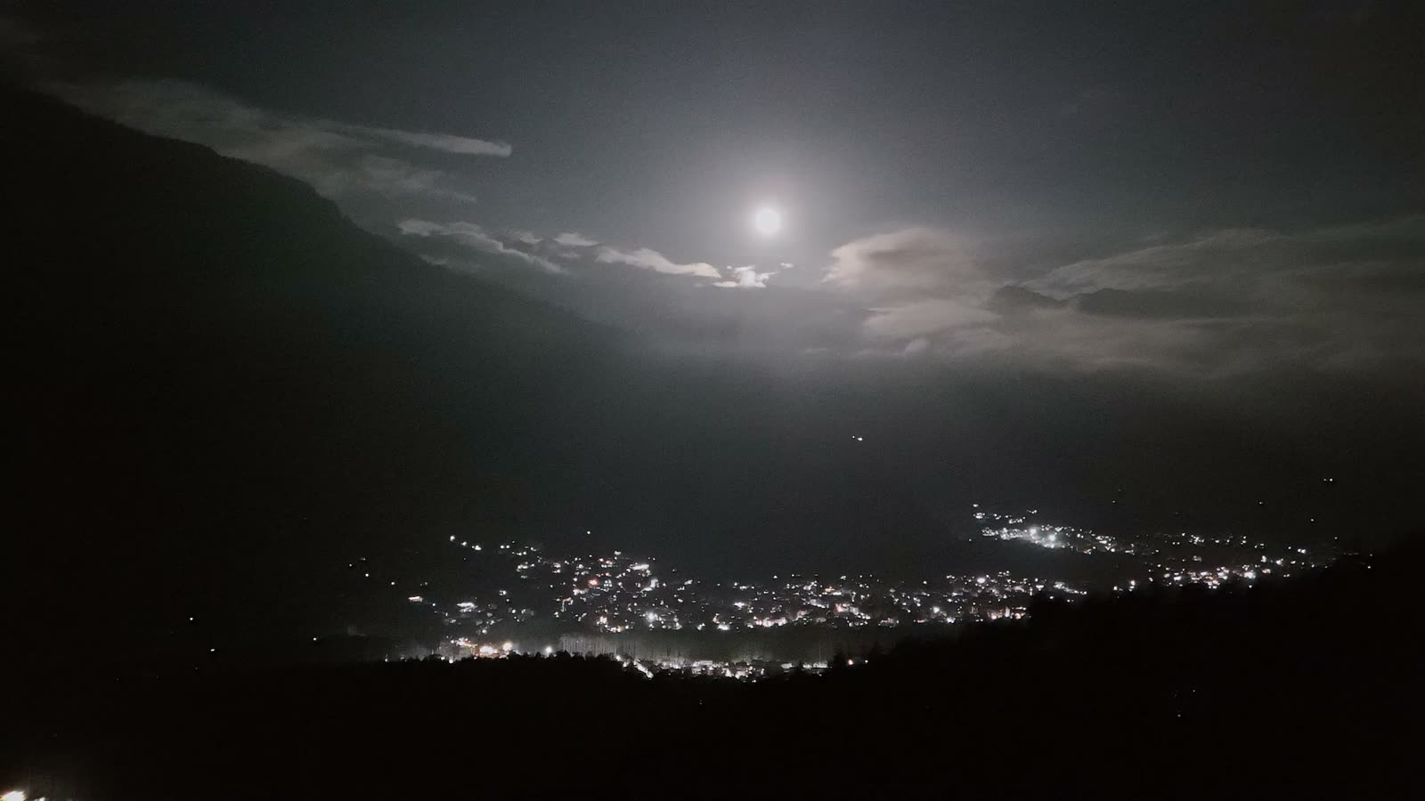 A moonlit sky above the lights of Manali valley at night.